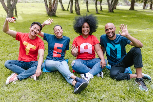 Fyra personer på en gräsmatta med matchande tröjor där det står "Team" representerar hållbart ledarskap