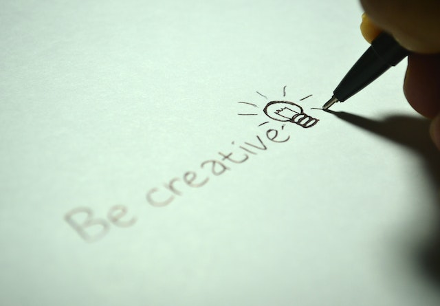 Någon som skriver Be creative på ett papper
